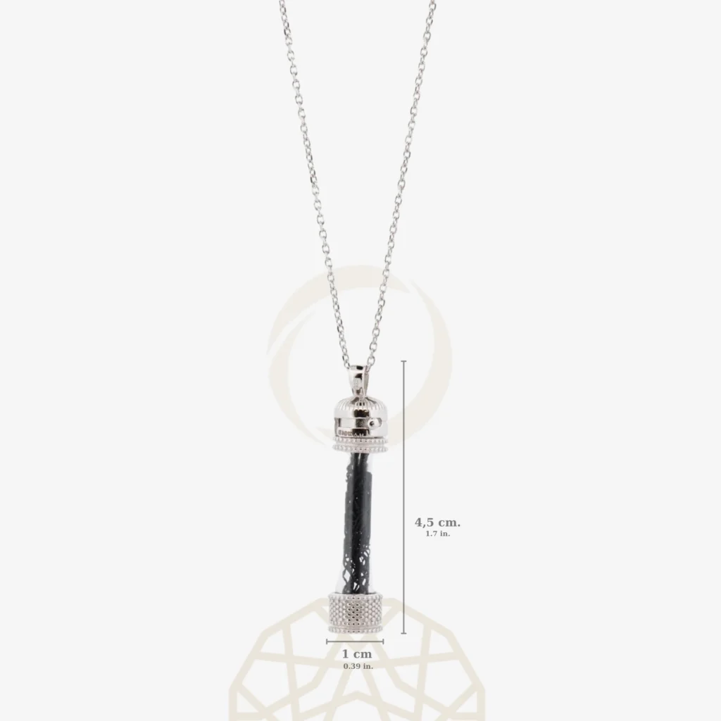 An aesthetic silver necklace made of 925 sterling silver, inspired by the cylindrical form of the historical Sakal-ı Şerif cases, with the original black Kaaba cover fabric visible inside its transparent case.
