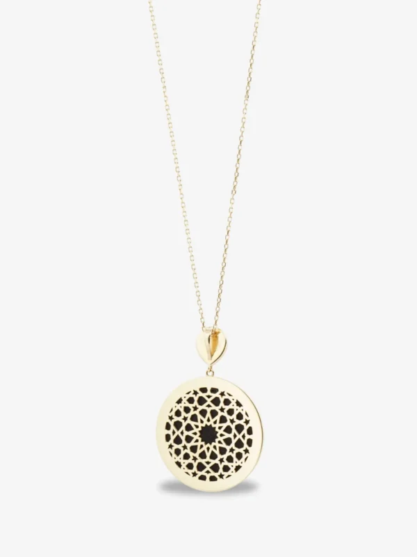 18 ayar altın pırlantalı yuvarlak madalyon kolye, merkezinde Kabe örtüsü ve arkasında geometrik kafes işçiliği olan mücevher.