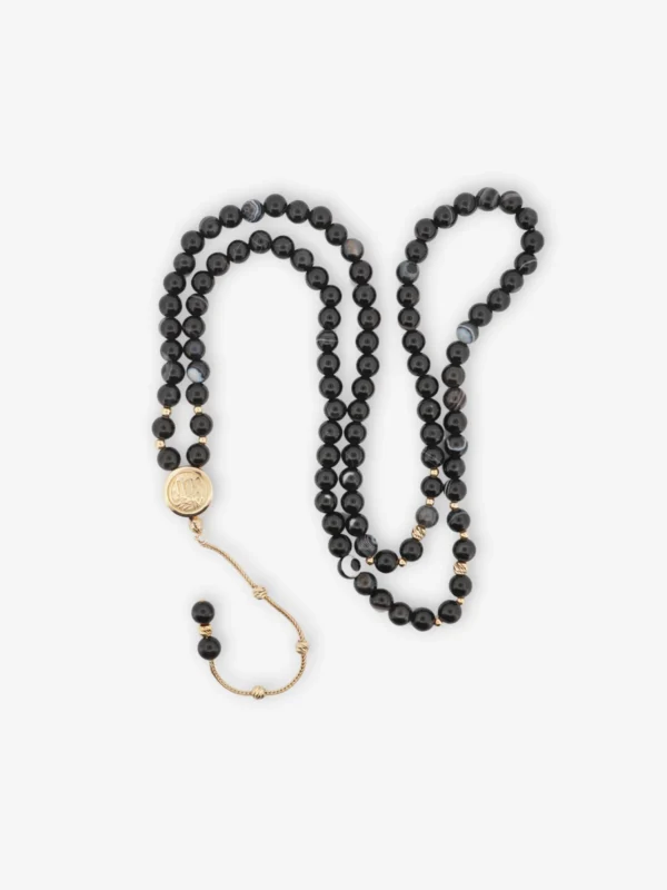 925 ayar gümüş, altın kaplama detaylı, 99 taneli siyah akik taşlı ve imamesinde orijinal Kâbe örtüsü bulunan vavlı kordon tasarımlı tesbih.